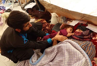 Shamaiel is lying on the floor of the medical tent with her young daughter next to her and her husband watching over them.