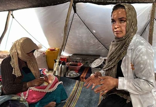 A midwife with a mother and newborn inside a tent being used as temporary recovery room at the maternity hospital in Herat City.