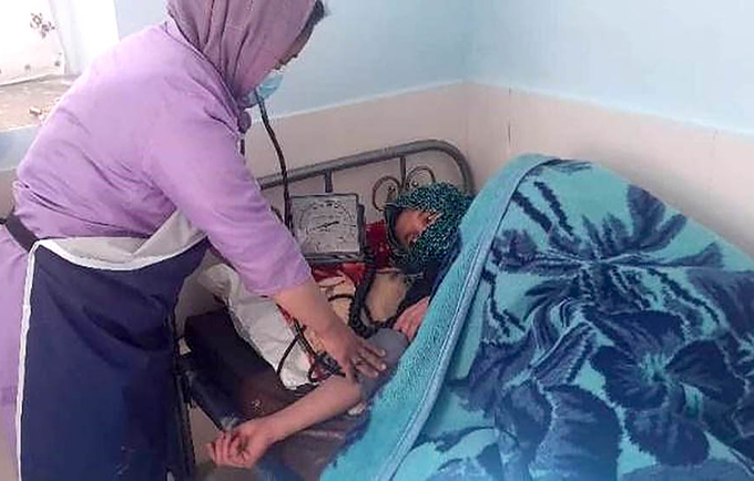 A midwife checking on a mother lying in bed after a childbirth