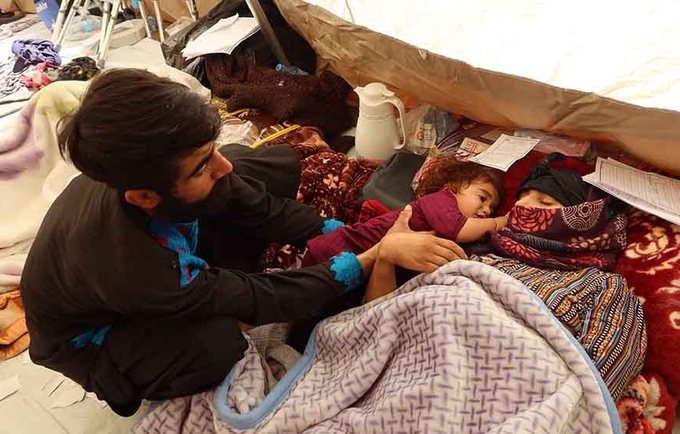 Shamaiel is lying on the floor of the medical tent with her young daughter next to her and her husband watching over them.