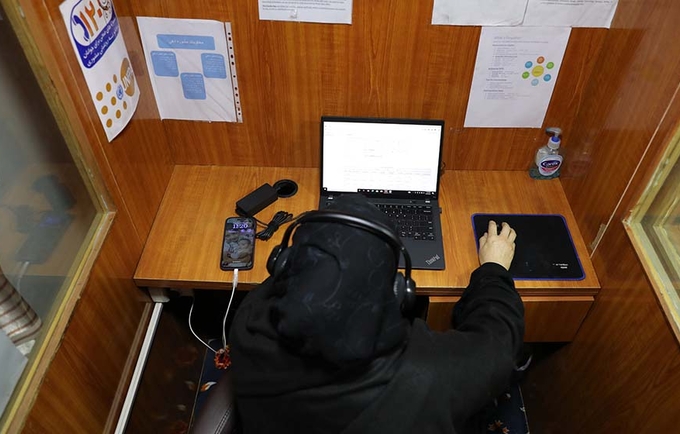 A woman in hijab with the headset in front of a computer