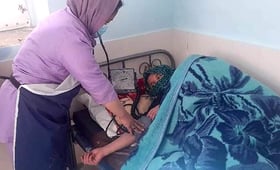 A midwife checking on a mother lying in bed after a childbirth