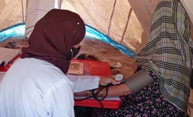 A midwife taking the blood pressure of a mother inside a tent clinic