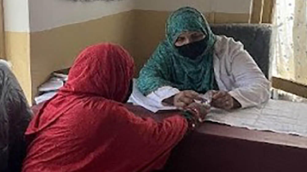 A woman in red hijab consulting a midwife inside a clinic