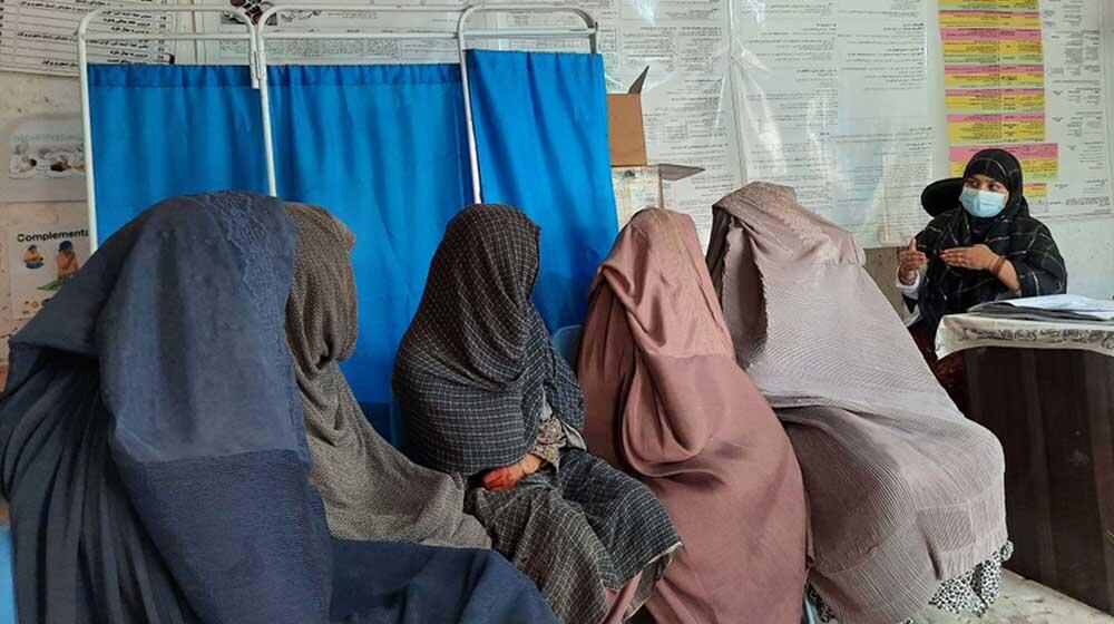 Five women wearing burqa listening to a midwife also wearing hijab