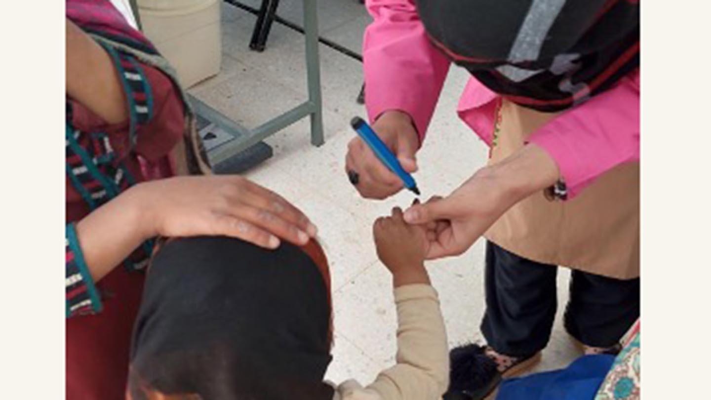 A midwife marks the finger of a child who just had polio vaccination.