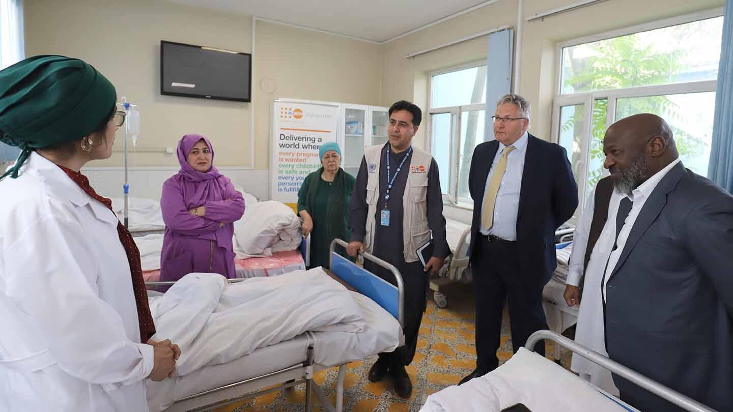 A female doctor speaking to men inside a hospital ward