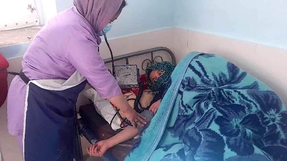 A midwife checking on a mother lying in bed after a childbirth