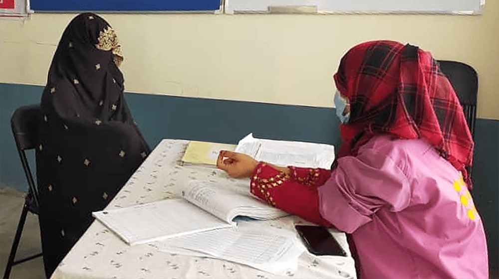 A woman in black burqa talking to a midwife