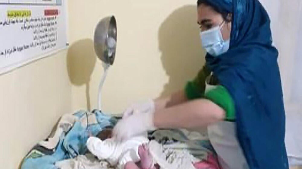 A midwife putting clothes on a newborn baby
