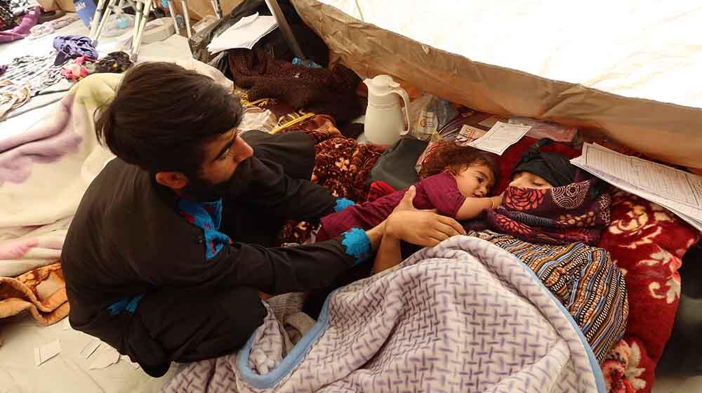 Shamaiel is lying on the floor of the medical tent with her young daughter next to her and her husband watching over them.