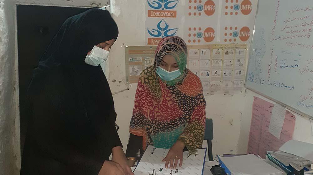 Midwives looking at patients' record book.