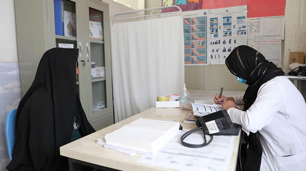 A woman in black burqa speaking to a midwife