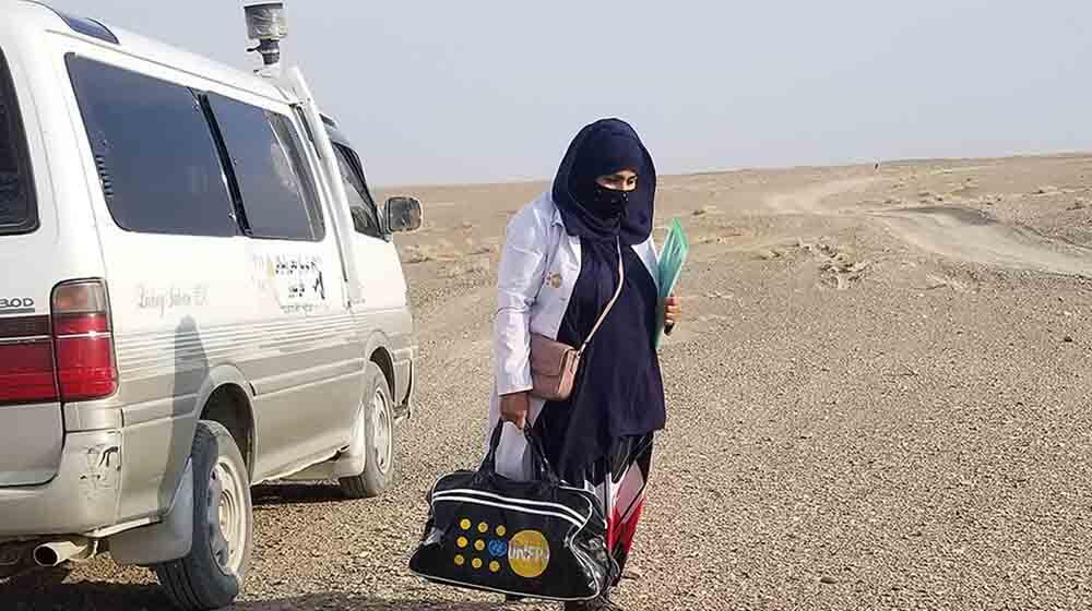 A midwife getting off the mobile health team car to meet a patient.