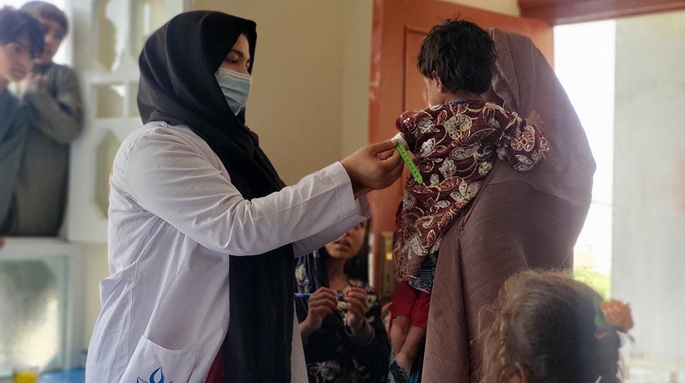 An Afghan midwife talking to a mother carrying a child.
