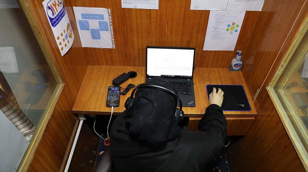 A woman in hijab with the headset in front of a computer