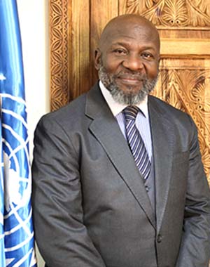 UNFPA Afghanistan Representative Kwabena Asante-Ntiamoah standing next to a UN flag